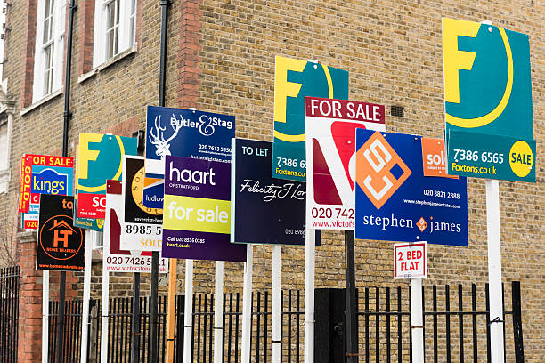 London, England, United Kingdom - February 11, 2015: FOR SALE and TO LET real estate agent signs outside residential housing development in Hackney. Many house rental and sales agency signs in a row. Multiple sign boards.